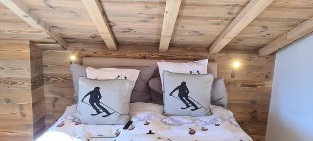 Appliques murales dans une chambre de chalet sous plafond à poutres