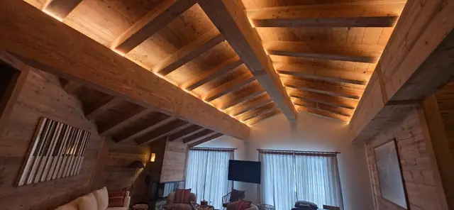Éclairage LED intégré aux poutres d'un salon de chalet