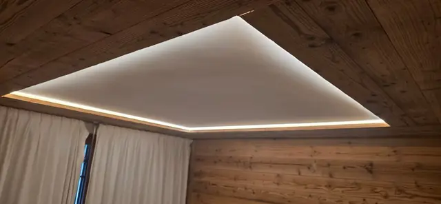 Faux plafond rétroéclairé LED dans une chambre boisée