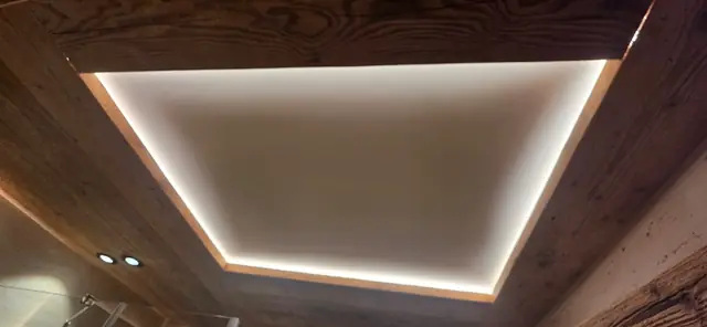 Gorge lumineuse LED et spots encastrés dans un plafond en bois
