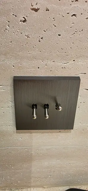 Interrupteurs à bascule design posés sur un mur en travertin