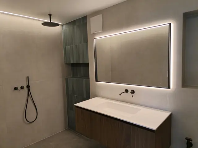 Miroir rétroéclairé LED et douche à l'italienne dans une salle de bain