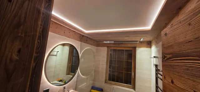 Salle de bain de chalet avec miroirs ronds LED et plafond lumineux