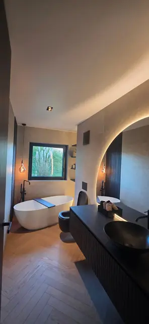 Salle de bain haut de gamme avec miroir arrondi rétroéclairé et baignoire îlot
