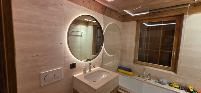 Salle de bain avec miroir rond LED et ruban lumineux au plafond