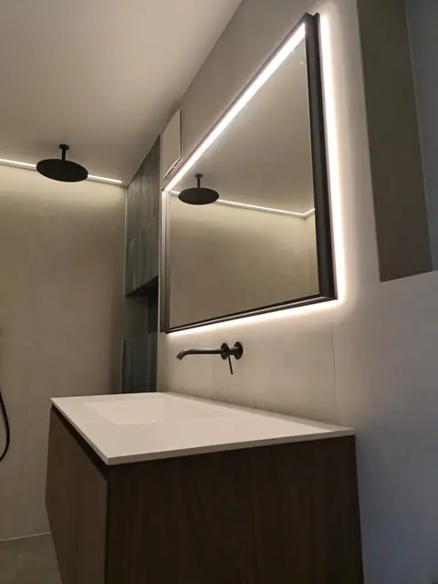 Salle de bain moderne avec miroir LED et ruban lumineux au plafond