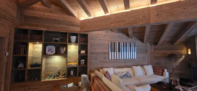 Salon de chalet avec bibliothèque éclairée et LED le long des poutres