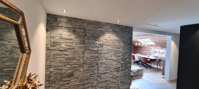 Spots LED encastrés dans un salon avec mur en pierre