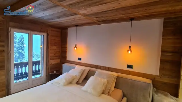 Suspensions lumineuses de part et d'autre du lit dans une chambre de chalet